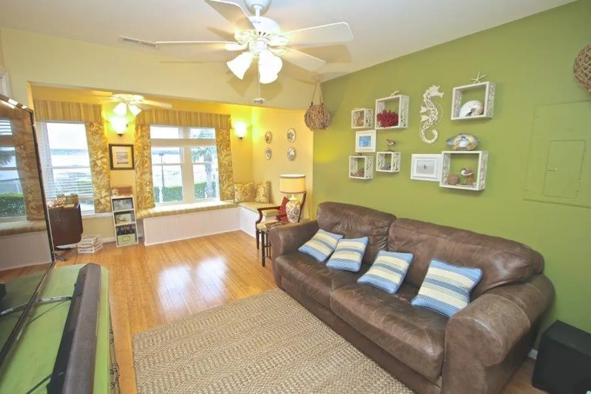 A cozy living area featuring a leather sofa, comfortable window seating, and sea-themed wall decor. The space is filled with natural light and offers an inviting spot for relaxation or socializing with loved ones.