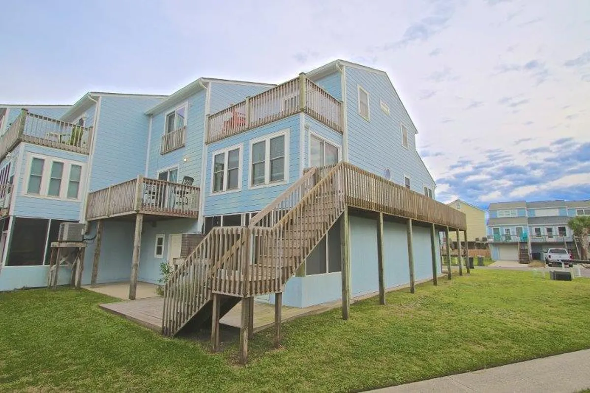 An exterior angle highlighting a wooden staircase, blue siding, and large windows. The view suggests easy access to outdoor spaces and a welcoming environment for family and pets alike.