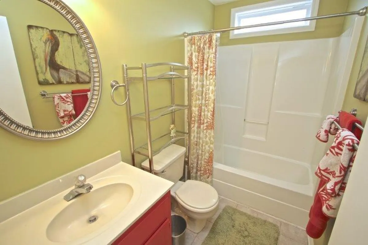 An inviting bathroom with a vanity and sink, colorful shower curtain, decorative mirror, and cheerful wall art. The space feels fresh, clean, and ideal for morning or evening routines.